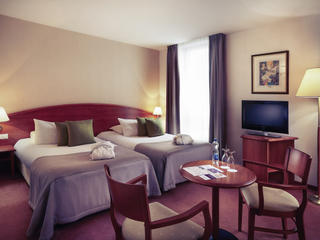 Гостиничный номер в Mercure Poznan Centrum в тёмных тонах &mdash; две двуспальных кровати, круглый столик, два кресла, тумба под ТВ