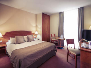 Гостиничный номер в Mercure Poznan Centrum в тёмных тонах &mdash; двуспальная кровать, прикроватные тумбочки, круглый столик, кресло, туалетный столик