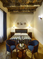 Гостиничный номер Делюкс &mdash; двуспальная кровать с высокой спинкой, прикроватные тумбочки, двустворчатый шкаф, два кресла с журнальным столиком &mdash; отель &Eacute;lite в центре Праги, Чехия.